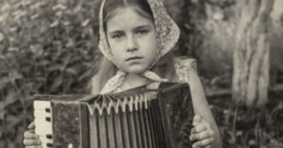 Девочка на крыше, сжимающая в руках тяжелый баян, смотрит вниз. Ещё секунда — и грохот разорванных мехов разбудит всю округу. Это не бунт. Это последний крик души, которую пытались втиснуть в чужую мечту